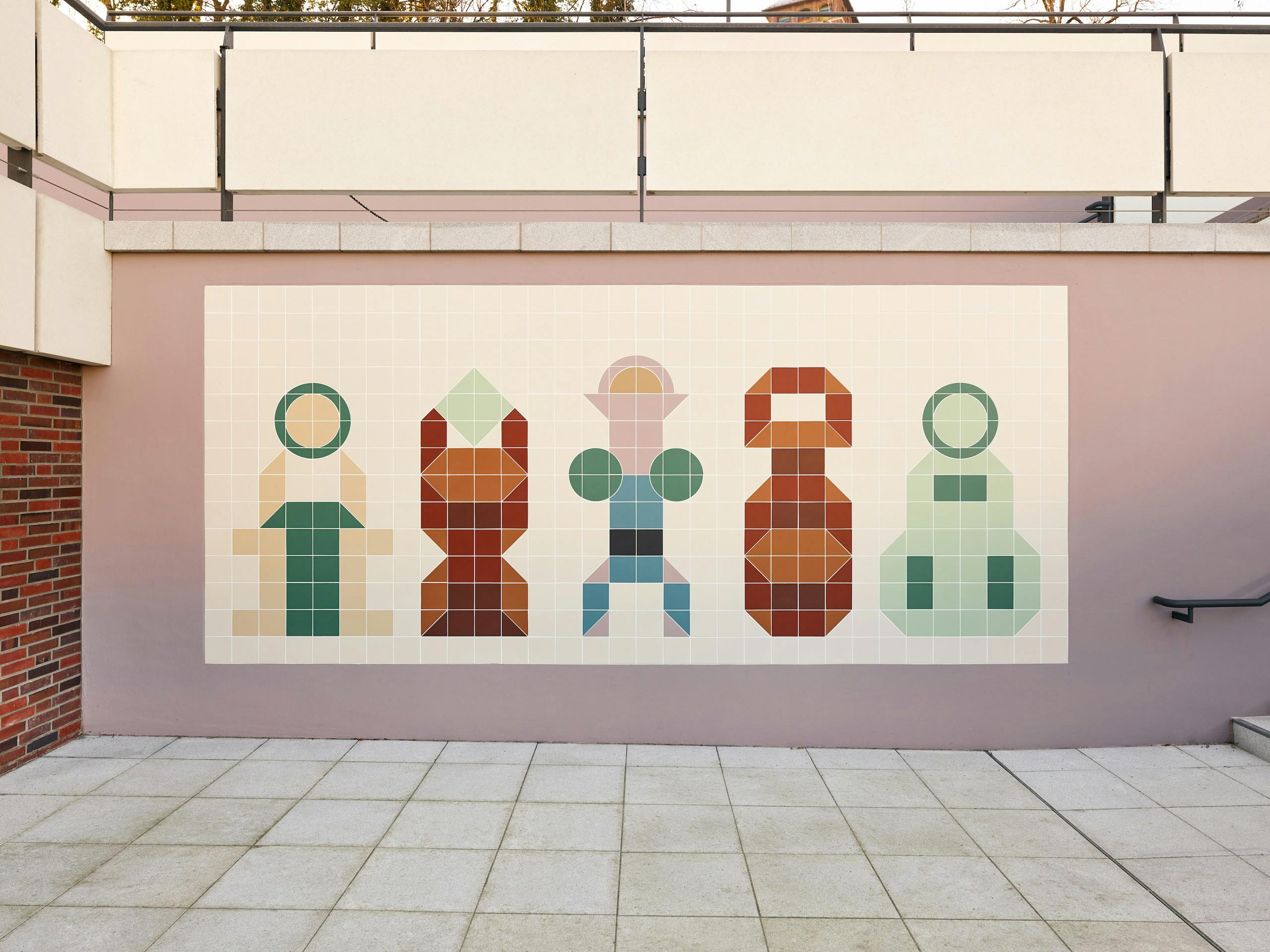 Foto einer großformatigen, farbigen Fliesenarbeit auf einer kleinen Terrasse des MINSK. Fünf Wesen sind stark vereinfacht gestaltet. Auf kantigen Körpern sitzen abwechselnd runde und eckige Köpfe. 
