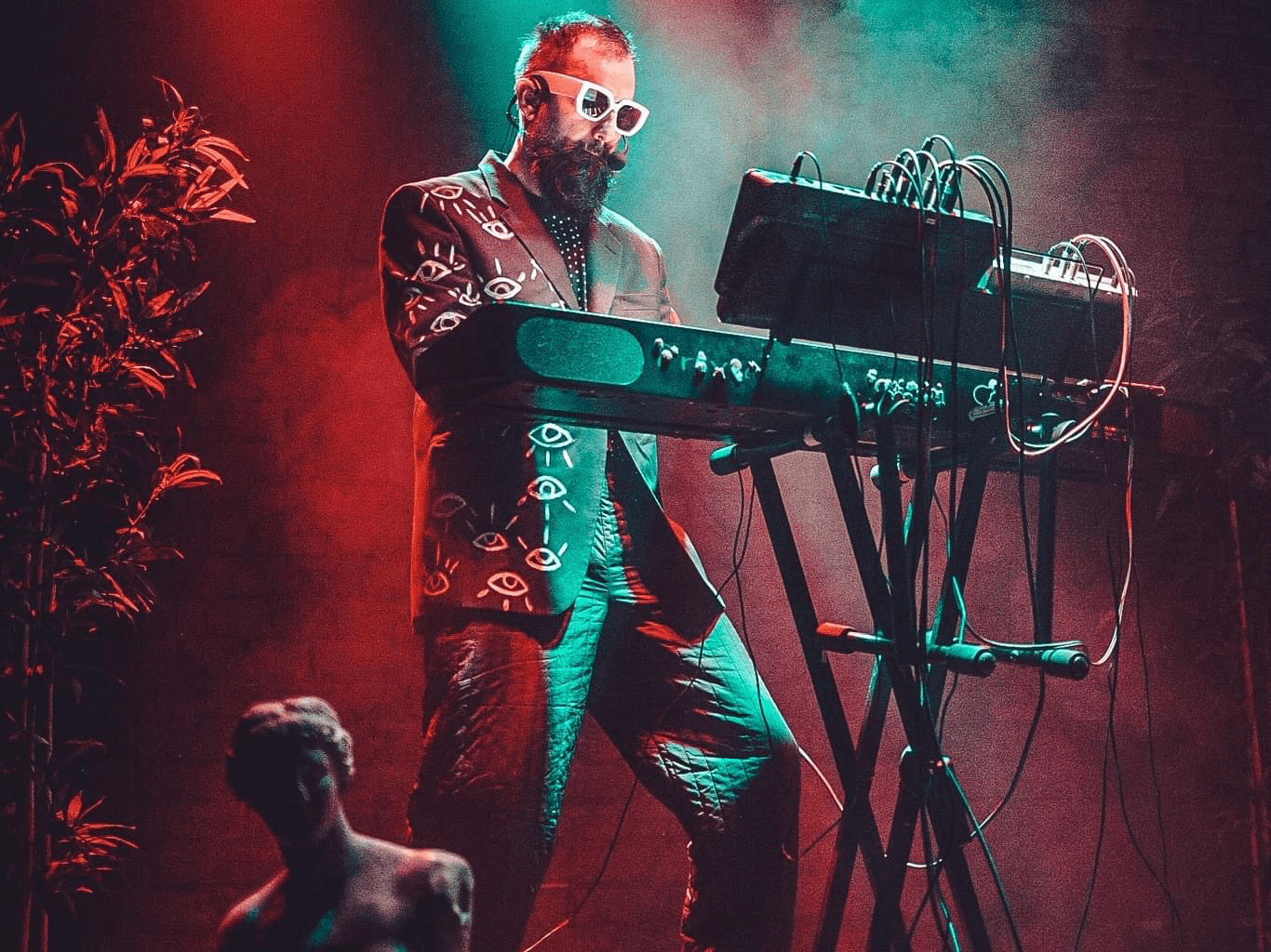 Photo of the musician K not K playing the electric piano on stage in the red spotlight. 