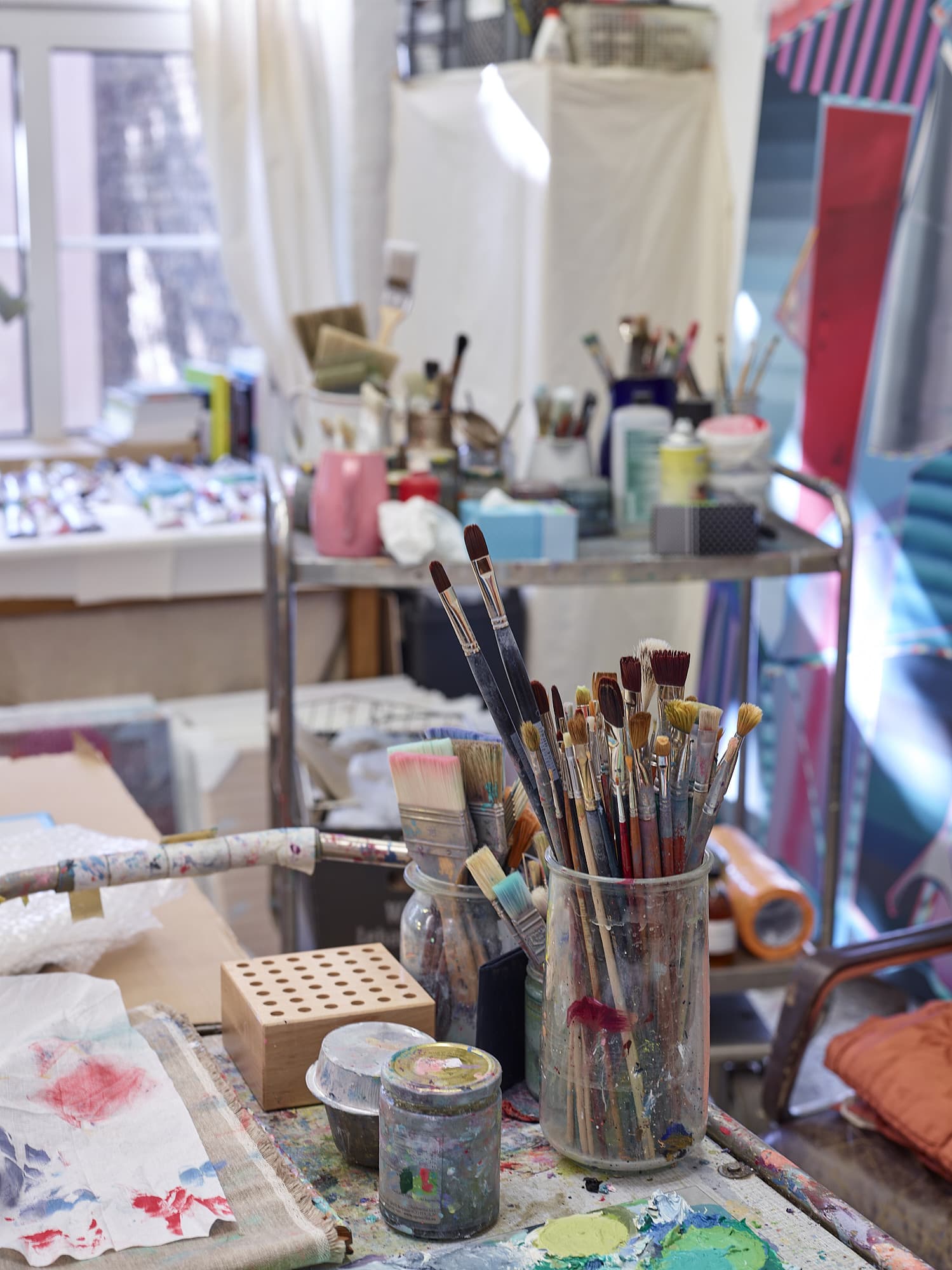 Foto: ein Innenraum. Alles ist für einen Kunst-Workshop vorbereitet. Gläser mit Pinseln sowie Farben und weitere Malutensilien stehen bereit. 