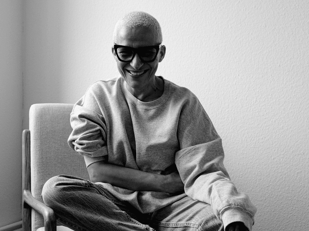 Photo in black and white of Peggy Kurka sitting in an armchair smiling. 