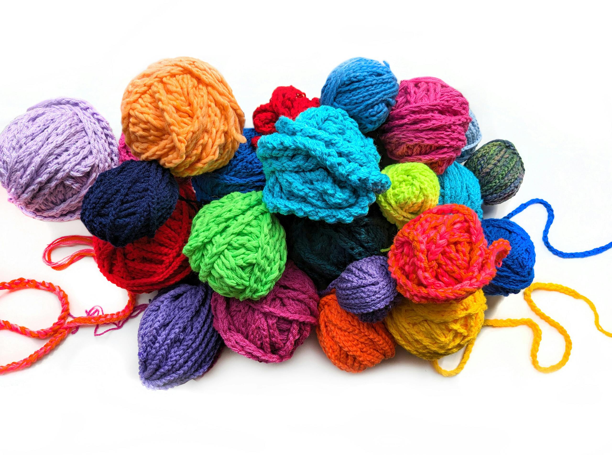 Photo: many colorful balls of wool are lying together in a pile, air stitches are wrapped around some of the balls